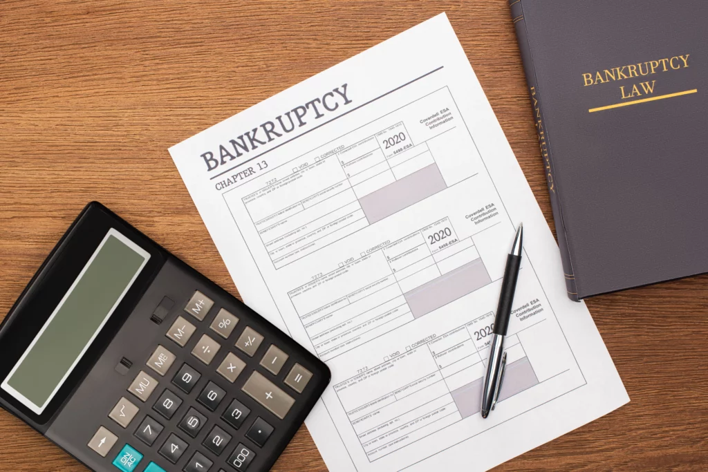 Bankruptcy Chapter 13 paperwork with calculator, pen, and law book on desk, representing financial eligibility for Georgia bankruptcy cases.