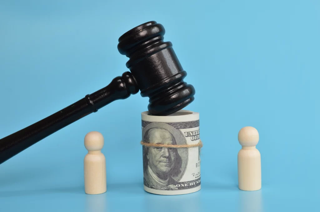 Judge’s gavel over rolled dollar bills between two wooden figures, symbolizing automatic stay protection from wage garnishment in bankruptcy cases.